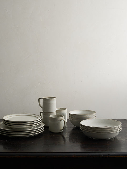 Set of white ceramic dishes on a dark table with a Roman clay background