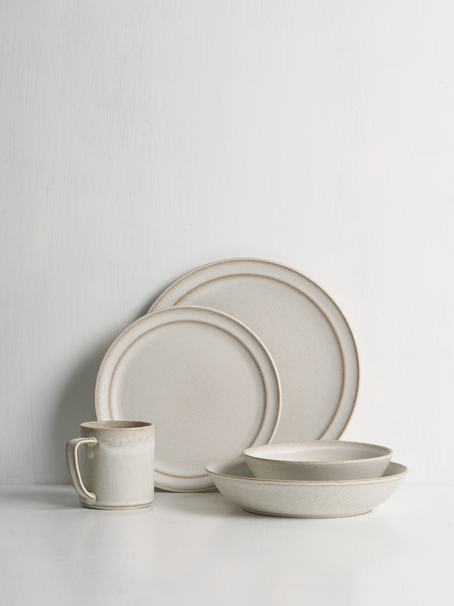 Set of ceramic dinnerware including plates and a mug on a light gray background