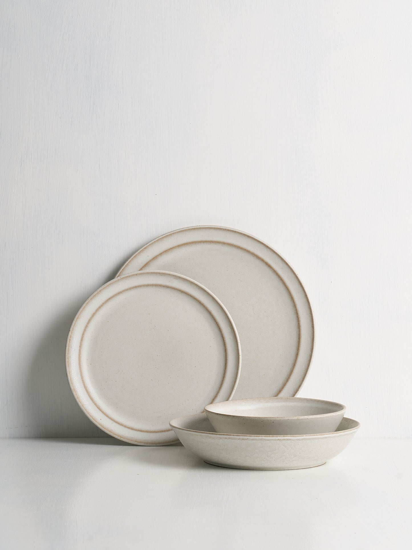 Set of ceramic plates and bowls with a beige rim on a white background