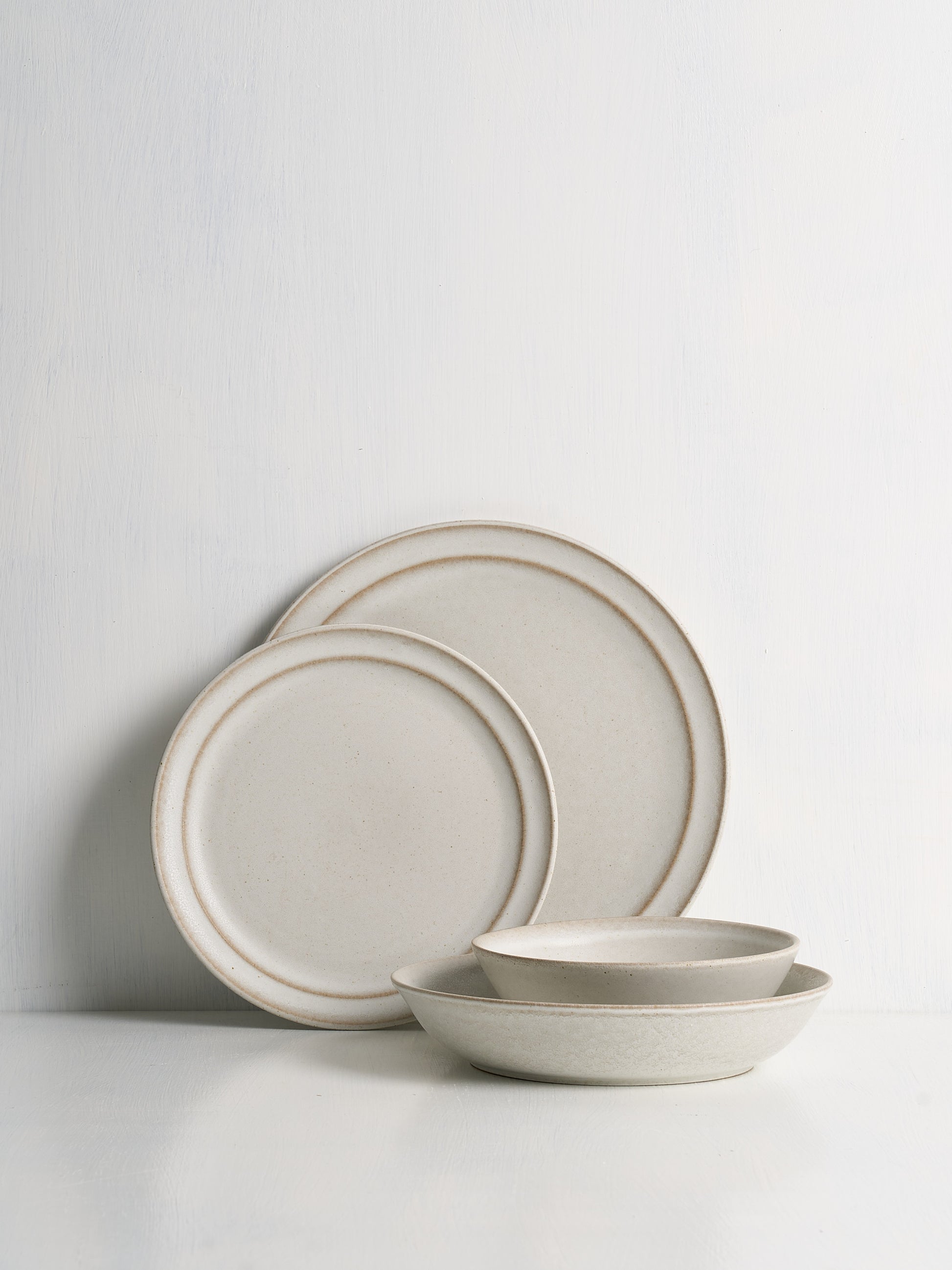 Set of ceramic plates and bowls with a beige rim on a white background