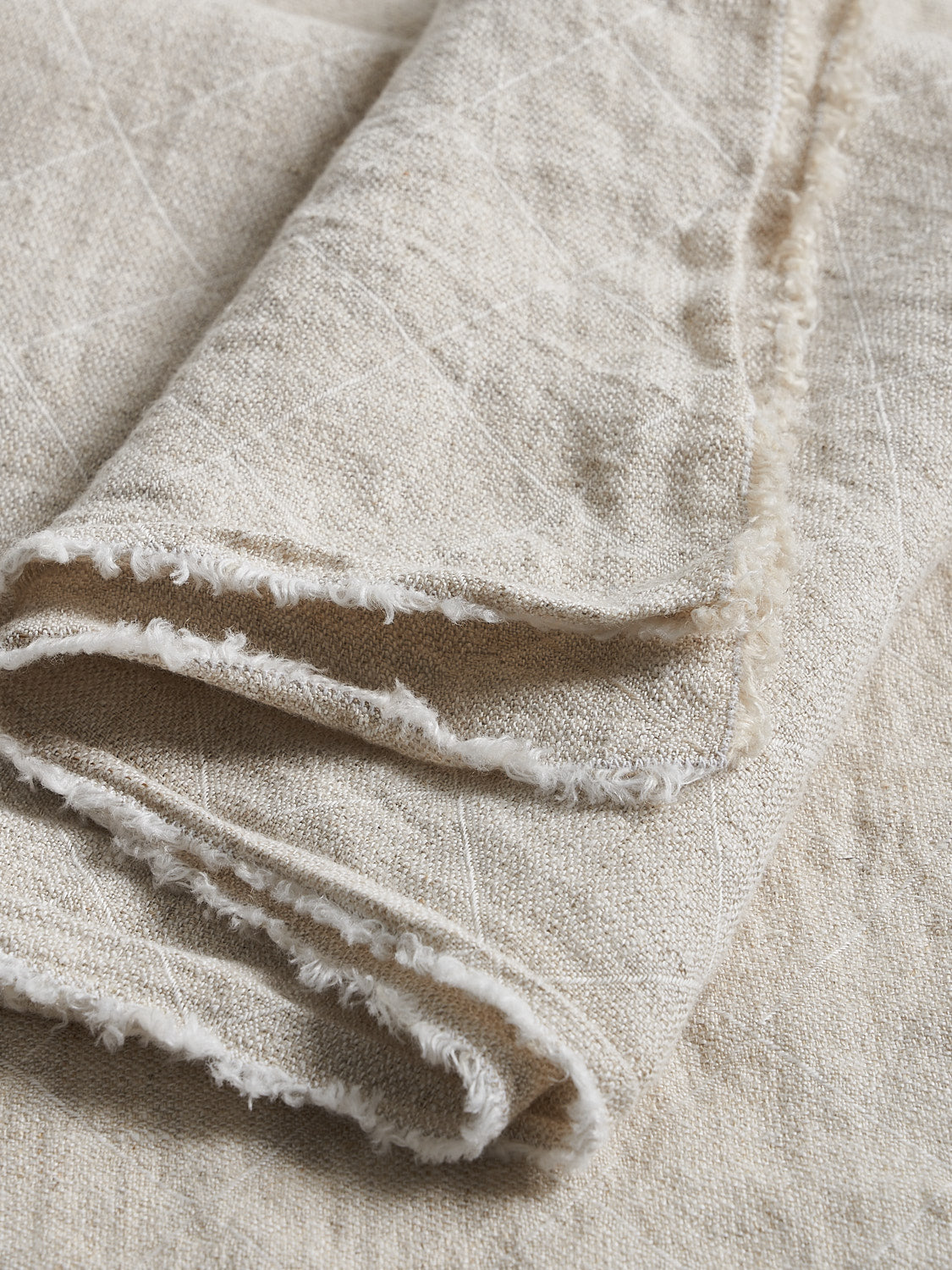 Close-up of a textured natural flax linen with grid jaqcuard and fringed edges