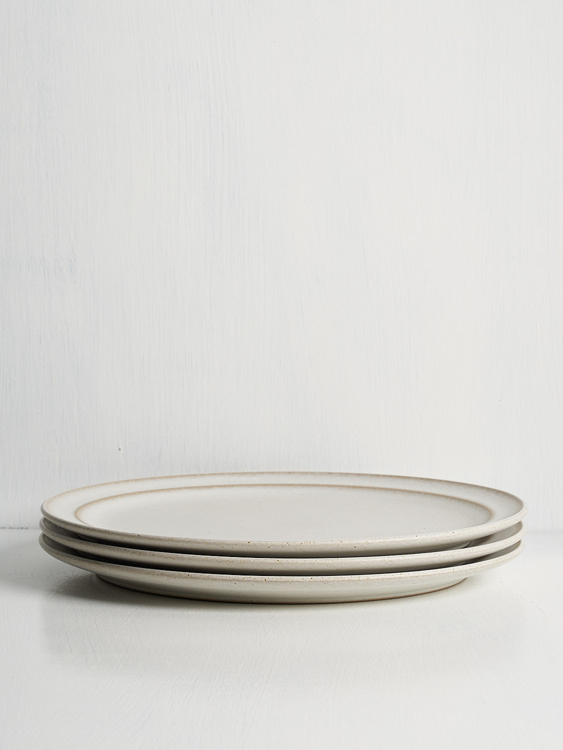 Stack of white stoneware dinner plates with refined design and timeless appeal