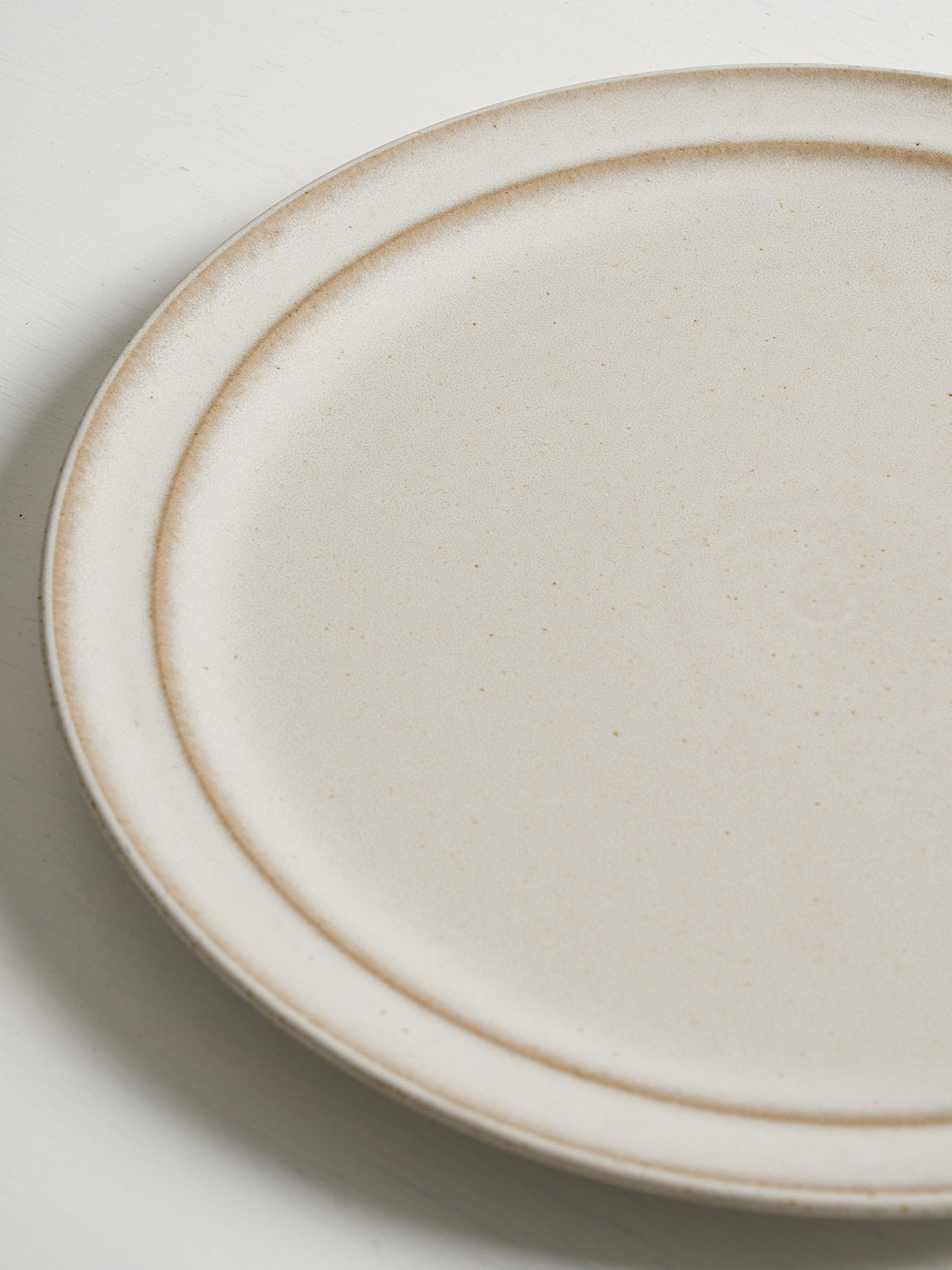 Close-up of ceramic plate edge showing subtle glaze variation and craftsmanship