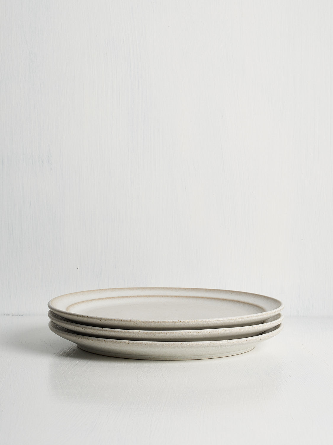 Stack of white stoneware side plates crafted in Portugal for everyday meals or hosting