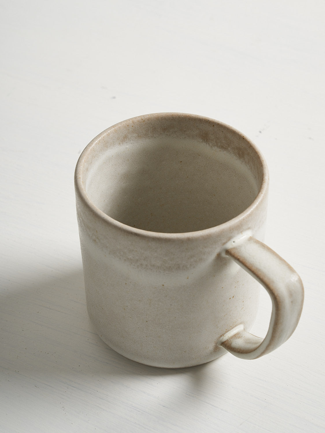 Detail of white mug rim and handle showing organic texture and artisanal glaze